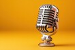 © Kalea - A vintage-style chrome microphone stands against a vibrant yellow backdrop, creating a retro and eye-catching visual contrast