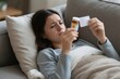 © Worldwide - A woman looks worried while reading a prescription bottle on the couch.