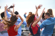 © pressmaster - Group of diverse young adults dancing outdoors with arms raised, enjoying energetic movement together, multiethnic men and women celebrating in open air setting, backs facing camera
