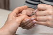 © mitsyko1971 - Nail care procedure in a beauty salon. Female hands and tools for manicure, process of performing manicure in beauty salon. Concept spa body care. Gloved hands of a skilled manicurist cutting cuticles
