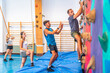 © unai - Trainer supporting climber on climbing wall in gym