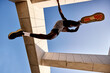 © Georgii - Athletic person jumping dynamically against a unique architectural urban setting under clear skies