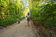 © dizfoto1973 - Woman and dog enjoy Nordic walking on a sunny forest path. Lush green trees create a vibrant, natural setting for a healthy outdoor adventure. Perfect for nature, exercise, and active lifestyle themes