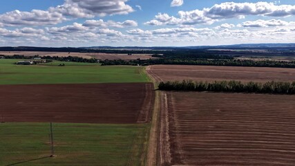 Wall Mural - Hyperlapse of floating and dissolving clouds over a landscape of fields and meadows from a drone