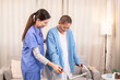 © Rakchanok - Young nurse assisting senior woman in walking with a walker, demonstrating caregiving, encouragement, and physical rehabilitation at home, healthcare, caregiver, medical, hospitality, recover.