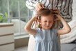 © Pixel-Shot - Mother checking her little daughter's head with pediculosis at home