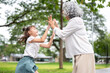 © bongkarn - Cute kid girl granddaughter clapping both hands with old woman grandmother in the park or garden.