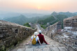 Travel tourists people sightseeing in China travel vacation. Happy interracial couple enjoying Great wall of China landscape near Beijing city. Asia travel summer holidays together.