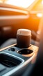 © jany sweet - Close-up of car cup holder with bottle on console in sunset light