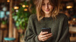 © vstudio - Casual young woman smiling and holding smartphone outdoors in warm sweater lifestyle candid portrait