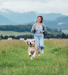 © Soloviova Liudmyla - Happy smiling beagle dog running portrait tongue out with female owner jogging along mountain meadow grass path outdoor walking nature pets healthy active people lifestyle concept image