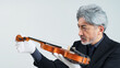© metamorworks - バイオリンを確認するミドルエイジ男性