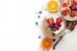 © TheWaterMeloonProjec - Nutritious morning meal with yogurt, muesli, and fresh fruits. Focused close-up with space for text. Overhead shot on white background, featuring healthful ingredients like milk, orange, and red