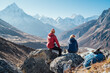 © Soloviova Liudmyla - Couple resting on the Everest Base Camp trekking route near Dughla 4620m. Backpackers left Backpacks and trekking poles and enjoying valley view with Ama Dablam 6812m peak and Tobuche 6495m