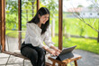 © Apichat - woman is sitting on a chair and typing on a laptop