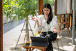 © Apichat - woman is sitting in a chair with a laptop in front of her