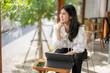 © Apichat - woman sits at a table with a laptop and a cell phone