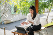 © Apichat - woman is sitting on a chair in front of a laptop, smiling