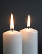 © Nabilatt - Two lit white candles on dark background