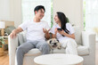 © tonefotografia - Couple Enjoys Quality Time at Home With Their Pug on a Cozy Couch in Bright Living Room