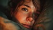 © SaroStock - Woman with freckles lies awake in bed early in the morning, looking thoughtful with soft lighting and focus on her beautiful features