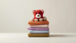 © karthik - Adorable red teddy bear plush toy sitting on a neat stack of colorful, soft, folded towels representing laundry day, cozy home comfort, and childhood innocence against a clean, minimalist background.