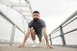 © Dusan Petkovic - Bearded Athletic Man in Gray T-shirt Preparing to Sprint on Contemporary Urban Bridge Structure