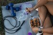 © Rangel - Muscular athlete consuming protein-rich meal while seated on yoga mat, surrounded by workout equipment like dumbbells and jump rope, representing dedicated fitness lifestyle