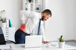 © Pixel-Shot - Young businessman suffering from back pain near table in office