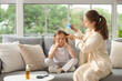 © Pixel-Shot - Mother combing her little daughter's hair with pediculosis on sofa at home
