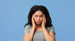 © Prostock-studio - Headache and migraine concept. African american lady suffering from hypertension over blue studio background, free space. Overworked woman feeling stressed, going through emotional crisis