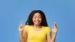 © Prostock-studio - Cherished wish. African american lady crossing fingers and smiling, begging for luck, praying for miracle, standing over blue studio background. Excited woman hoping for good things to happen