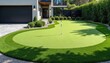 © miss irine - Rich green golf putting green in residential yard, featuring flag. Sunny day illuminates artificial turf, ideal for backyard practice, hobby golfers. Modern house, manicured landscaping surround.