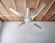 © Karina - rotating white ceiling fan against a white ceiling and brick wall backdrop