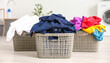© AlgoCreative - Three laundry baskets filled with colorful clothes are placed on light wooden floor, creating vibrant and organized scene in modern laundry room