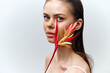© VICHIZH - Elegant young woman with tropical flower, showcasing beauty and emotions in a minimalist setting, perfect for fashion and wellness themes.