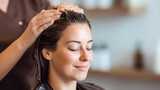 Hairdresser applying oil treatment to woman's hair in salon