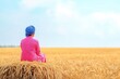 © pitchanat - Woman sitting in a wheat field du daytime horizon landscape with blue sky and clouds in the background peaceful rural scene sunny agricultural environment