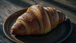 © Yasin - Golden brown croissant on a rustic wooden table with soft lighting