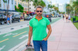 Hispanic man traveler outdoor. Tourist traveler on spring vacation. The travelers luggage for spring trip. Summer tour. A tropical getaway. Spring break. A traveler enjoys summer day. Summer trip.