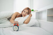 © WMSTUDIO - Young woman relaxing in bed reaching for alarm clock, bright and airy interior, morning routine, lifestyle mood, waking up feeling fresh and happy
