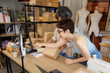 © SHUTTER DIN - two Asian women packing products in their clothing design studio.