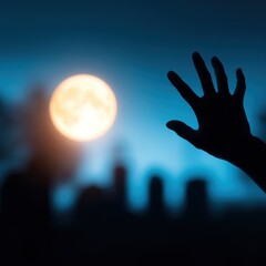 Wall Mural - Silhouetted hand reaching towards a bright full moon over a dark, mysterious graveyard at night