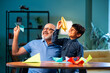 © StockImageFactory - Indian grandfather and child making paper boat or aeroplane together at home