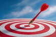 © HrdiGn Std - Red dart in center of bullseye on white board against blurred blue sky with white clouds