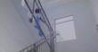 © vectorfusionart - Ascending mid-adult nurse wearing blue scrubs climbing stairwell with handrail, window, copy space