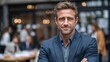 © rifai_art - Confident man in a suit smiles at the camera, blurred restaurant background