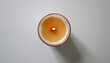 © Lesia - Lit candle in glass holder, shot from top down perspective. Soy candle with wooden wick. Placed in center of white background. Warm glow of flame creates cozy atmosphere, ideal for of relaxation.