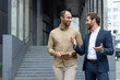 © Liubomir - Two businessmen talking and walking outside office building