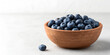 © AKLIMA - Clay bowl filled with fresh blueberries styled on neutral background in natural eco food design